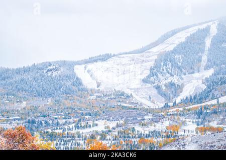 Aspen, Colorado, Stadthäuser in felsigen Bergen, die während der Herbstsaison aus einem hohen Blickwinkel das Tal der Gabelung brüllen und in einen verschneiten Winter mit gelbem Schnee überwechseln Stockfoto