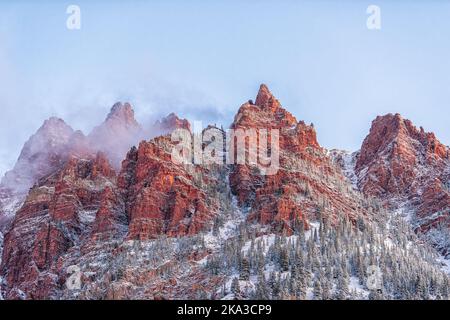 Nahaufnahme von Maroon Bells in Aspen, Colorado, Red Mountains, rauer Gipfel bei Sonnenaufgang mit Schneespitzen im Spätherbst mit Nebelwolken im Winter Stockfoto