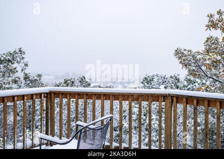 Haus-Haus-Immobilien mit einem hohen Winkel Blick auf Herbstlaub auf Bäumen mit Schnee bedeckenden Blättern und Stuhl auf Holzterrassengeländer Stockfoto