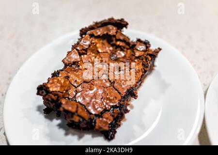 Makro-Nahaufnahme eines hausgemachten gebackenen Brownie-Schokoladenkuchenstückes Dessertbrot, süßes Essen mit Krümeln auf Küchentischplatte auf weißem Hintergrund Stockfoto
