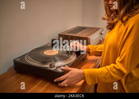 Beschnittene anonyme Meloman, die Stylus auf Vinyl-Schallplatte auf altmodischem Plattenspieler platziert Stockfoto