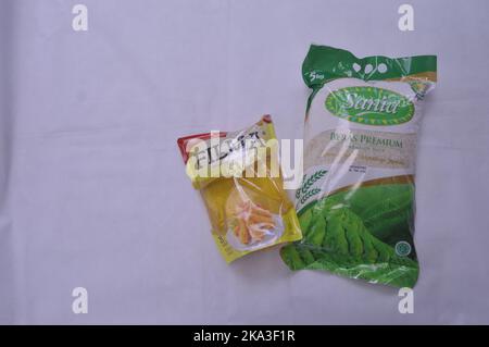 Verpackter Reis und Speiseöl auf weißem Hintergrund Stockfoto