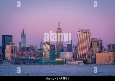 Moderne Wolkenkratzer und das Empire State Building am Ufer der New York Bay gegen den Sonnenuntergang in Manhattan Stockfoto