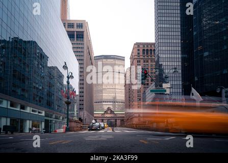 Autos, die an sonnigen Tagen in Manhattan, New York, USA, auf der Straße in der Nähe von Hochhäusern vor wolkenlosem, blauem Himmel fahren Stockfoto