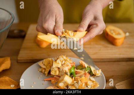 Von oben der Ernte unkenntlich Frau Schneiden reifen frischen Squash mit Messer während der Vorbereitung Abendessen in der Küche Stockfoto