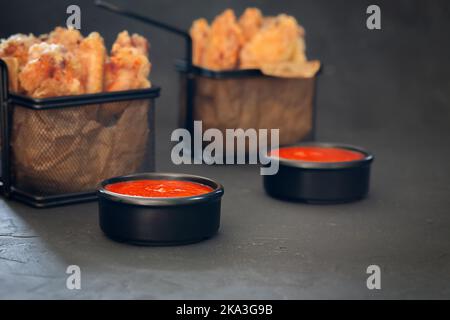 Köstlicher Ketchup in einer Schüssel mit Buffolo-Flügeln im Hintergrund Stockfoto