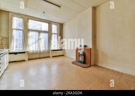 Leeres altes Zimmer neben hellem Fenster und Parkettboden mit Kamin Stockfoto