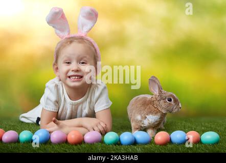 Nettes kleines Mädchen mit einem Hasen Kaninchen hat ein ostern auf grünem Gras Hintergrund mit Kopieplatz Stockfoto