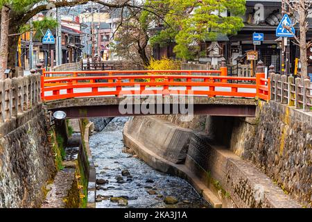 Takayama, Japan - 6. April 2019: Kleine leuchtend rote Brücke über den Fluss Enako in der Präfektur Gifu in Japan, Bergstadt mit Wasser in der Stadt Stockfoto