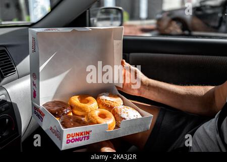 Neapel, USA - 27. Oktober 2021: Mann hält ein halbes Dutzend Dunkin Donuts Donuts in einem Karton-Container-Box, glasiert frittiertes Dessertgebäck von Bos Stockfoto
