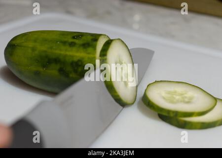 Gurke auf Schneidebrett, in Scheiben schneiden. Stockfoto
