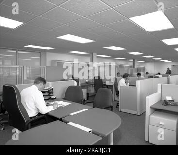 1989, historisches, halboffenes Büro, männliche Mitarbeiter, die an Schreibtischen in Kabinen arbeiten, Büroleiter an seinem Schreibtisch mit Blick auf die Büroetage, England, Großbritannien. Stockfoto