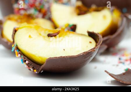 Stücke Süßigkeiten Apfel mit Milchschokolade überzogen und mit bunten süßen Streuseln, Süßwaren bedeckt Stockfoto