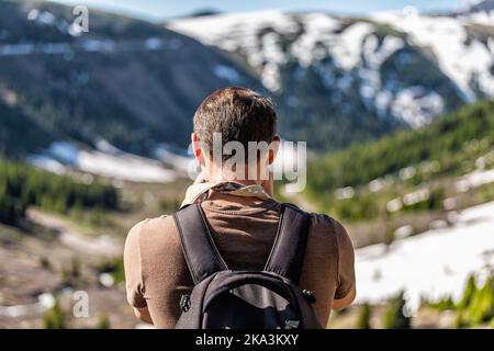 Mann, der im Frühsommer mit Schneeräck einen Blick aus der Höhe auf dem Linkins Lake Trail auf dem Independence Pass in den felsigen Bergen in der Nähe von Aspen, Colorado, fotografiert Stockfoto