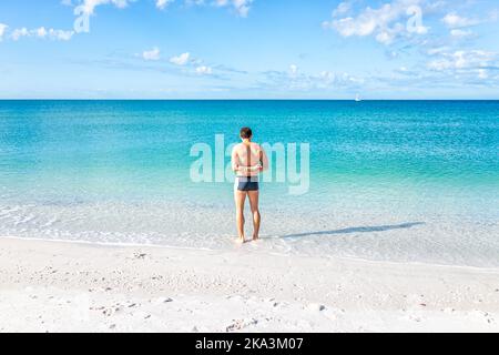 Junger, muskulöser, erwachsener Mann am Barefoot-Strand von Bonita Springs in der Nähe von Naples, Florida, der im klaren, türkisfarbenen Meer am Golf schwimmt Stockfoto