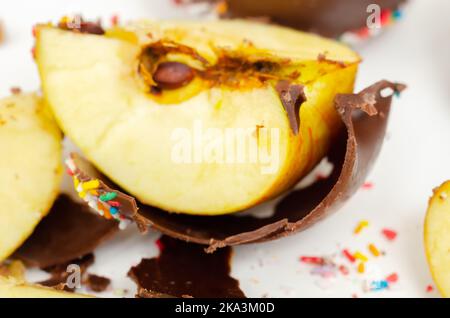 Stücke Süßigkeiten Apfel mit Milchschokolade überzogen und mit bunten süßen Streuseln, Süßwaren bedeckt Stockfoto