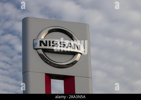 Polen, Poznan - 30. Oktober 2022: Nissan Autohersteller japanisches Firmenlogo, Himmel Hintergrund außen. Stockfoto