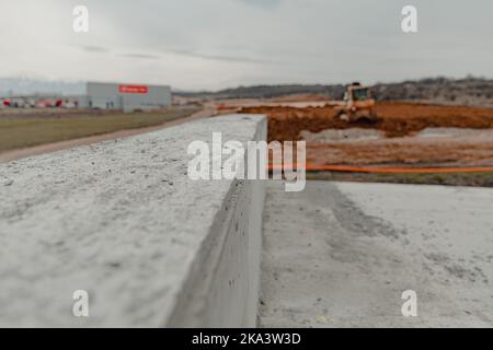 Eine selektive Fokusaufnahme von Betontreppen auf dem unscharfen Hintergrund schwerer Industriemaschinen Stockfoto