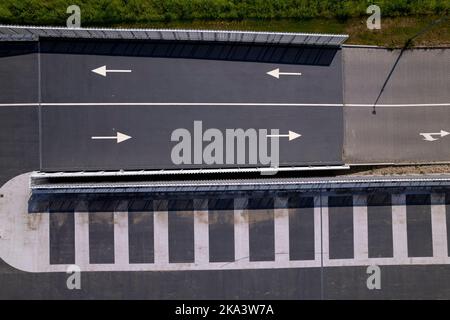 Richtungspfeile von oben nach unten Luftbild mit grafischer Umrisse Parkplatz mit Pfeilen und Flecken in der dunklen Asphalt auf erhöhten Dach markiert. Stockfoto