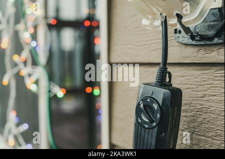 Outdoor-Timer und GCFI-Ausgang mit Abdeckung. Verschwommenes weihnachtslicht im Hintergrund. Stockfoto