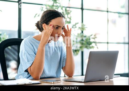 Überrascht frustrierte, gemischte Büroangestellte, die an einem Schreibtisch im Büro sitzen, enttäuscht auf den Laptop-Bildschirm schauen, schlechte Nachrichten lesen, schlechtes Arbeitsergebnis erzielen, negative Emotionen erleben Stockfoto
