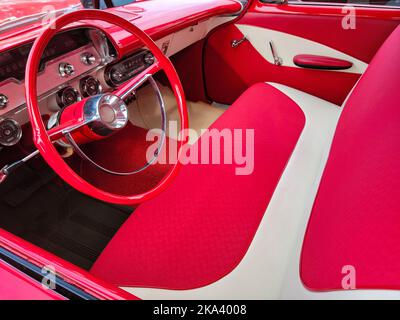 Innenraum mit leuchtend roten und weißen Oldtimern, Sitzbank und Lenkrad Stockfoto