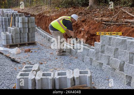 Bauarbeiter baut eine Stützblockwand auf einem neuen Grundstück, das gerade gebaut wird Stockfoto