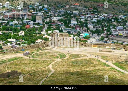 Szenische High-Angle-Ansicht der genuesischen Festungsmauer mit Haupttor und Uyutnoye Lage dahinter in Sudak Stadt, Krim, Russland. Stockfoto