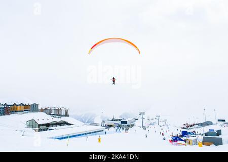 Gudauri Skigebiet Panorama mit Tandem Gleitschirme fliegen über Skifahrer im Skigebiet in kalten Wintertag Stockfoto