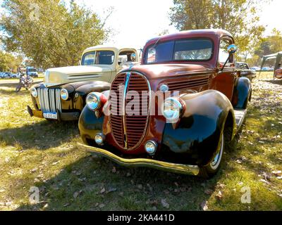 Alte rot-schwarze LKW-Pickup Ford 85 V8 1938 - 1939 auf dem Land. Naturrasen und Bäume. Oldtimer-Show. Stockfoto