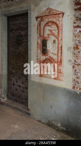 San Benigno Canavese, Piemont, Italien - 23. Oktober 2022: Tür aus dem Mittelalter und antikes Fresko an der Wand. Stockfoto