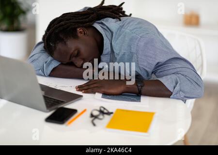 Schlafen Bei Der Arbeit. Müde Afroamerikanischer Mann, Der Am Schreibtisch Mit Laptop Nippt Stockfoto