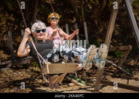 Zwei ältere Frauen schwingen freudig auf einer Schaukel Stockfoto