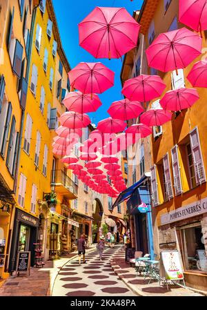Grasse, Frankreich - 6. August 2022: Historische Mietshäuser und enge Straßen mit rosa Regenschirmen aus dem alten Stadtviertel der Parfümerie-Stadt Stockfoto
