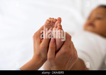 Baby-Reflexzonenmassage. Mutter Massierte Kleine Füße An Ihrem Schwarzen Kleinkind Stockfoto