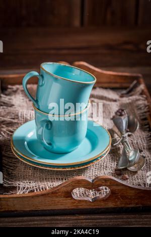 Einige blaue Kaffeetassen mit Löffeln auf altem Holztablett Stockfoto