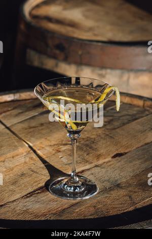 Wodka, Gin martini mit einem langen Zitronenwist in der Sonne auf einem Bourbon-Whiskey-Fass Stockfoto