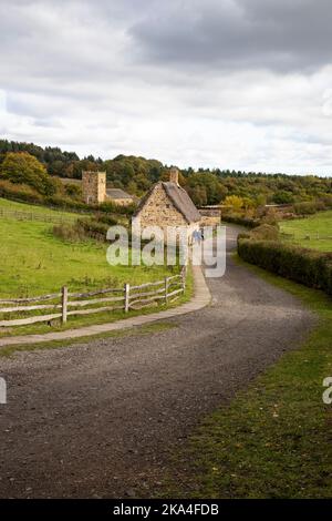 Eine rekonstruierte Szene aus dem frühen 19.. Jahrhundert einer typischen strohgedeckten Hütte und Kirche aus der georgischen Zeit im Beamish Museum, Co. Durham, Nordengland Stockfoto