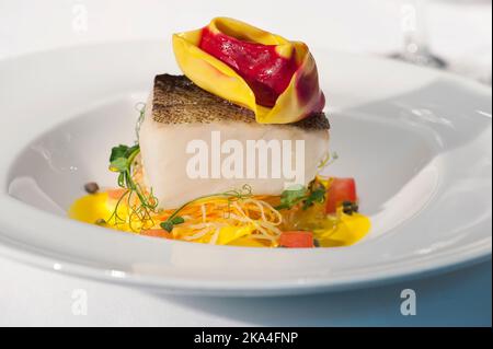 Weißer Fisch serviert mit einem gefüllten Tortellon auf einer gelben Creme Stockfoto