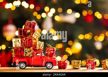 Roter Retro-Spielzeugtruck trägt Geschenke auf dem Hintergrund des Weihnachtsbaums Stockfoto