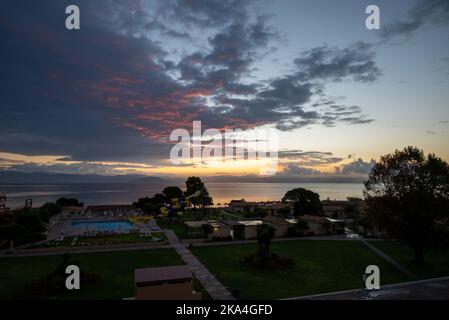 Sonnenaufgang Von Der Insel Korfu Mit Blick Auf Die Berge Der Balkanhalbinsel Griechenlands, Moraitika, Korfu, Griechenland. Im Vordergrund Sind Silhouetten Von Bäumen Stockfoto