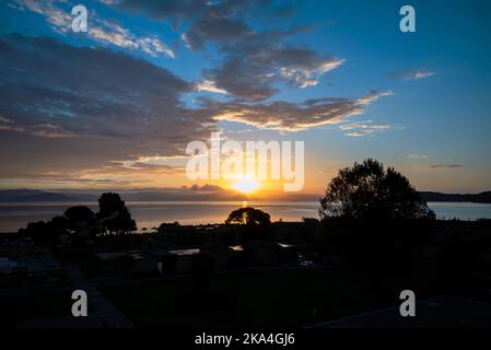 Sonnenaufgang Von Der Insel Korfu Mit Blick Auf Die Berge Der Balkanhalbinsel Griechenlands, Moraitika, Korfu, Griechenland. Im Vordergrund Sind Silhouetten Von Bäumen Und Stockfoto