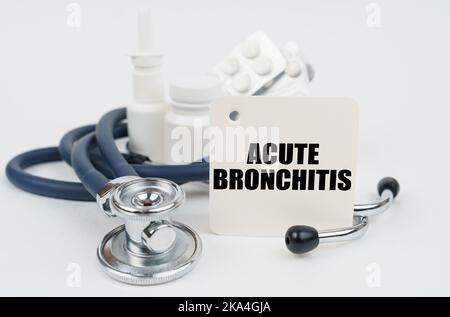 Medizinisches Konzept. Auf einer weißen Oberfläche, Medikamente, ein Stethoskop und Schreibpapier mit dem Text - akute Bronchitis Stockfoto