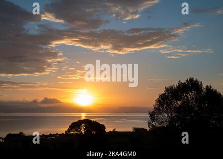 Sonnenaufgang Von Der Insel Korfu Mit Blick Auf Die Berge Der Balkanhalbinsel Griechenlands, Moraitika, Korfu, Griechenland. Im Vordergrund Sind Silhouetten Von Bäumen Und Stockfoto