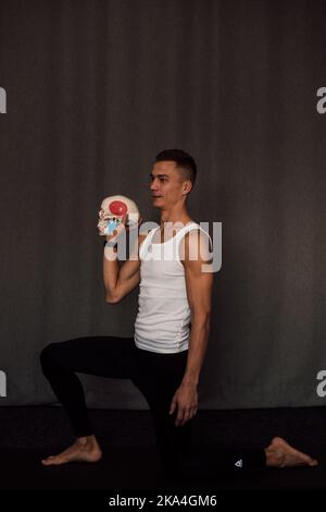 Ein weißer Schädel in den Händen eines Mannes. Anatomie Stockfoto