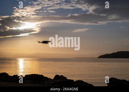 Silhouette Der Drohne, Die Über Den Pier Fliegt. Sonnenaufgang Von Der Insel Korfu Mit Blick Auf Die Berge Der Balkanhalbinsel Griechenlands, Moraitika, Korfu, Griechenland Stockfoto