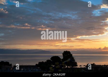 Sonnenaufgang Von Der Insel Korfu Mit Blick Auf Die Berge Der Balkanhalbinsel Griechenlands, Moraitika, Korfu, Griechenland. Im Vordergrund Sind Silhouetten Von Bäumen Stockfoto