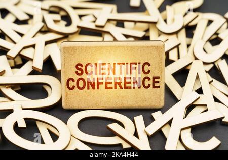 Bildungskonzept. Unter den hölzernen Buchstaben ist ein Schild mit der Inschrift - Wissenschaftliche Konferenz Stockfoto