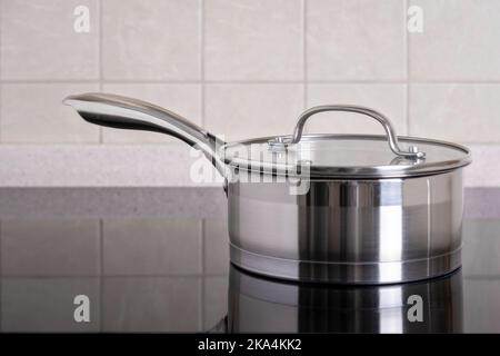Auf dem modernen Herd mit Glaskeramikkochfeld befindet sich eine Schöpfkelle aus Edelstahl. Stockfoto