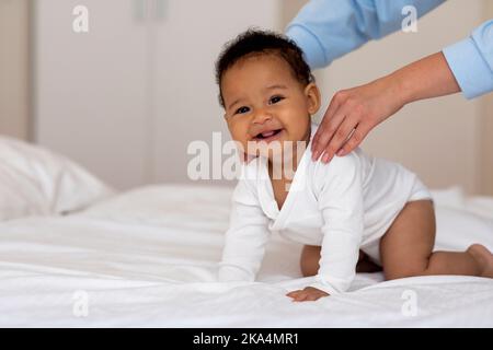 Liebenswert Schwarz Baby Bekommen Massage Aus Liebevolle Mutter Beim Entspannen Auf Bett Stockfoto